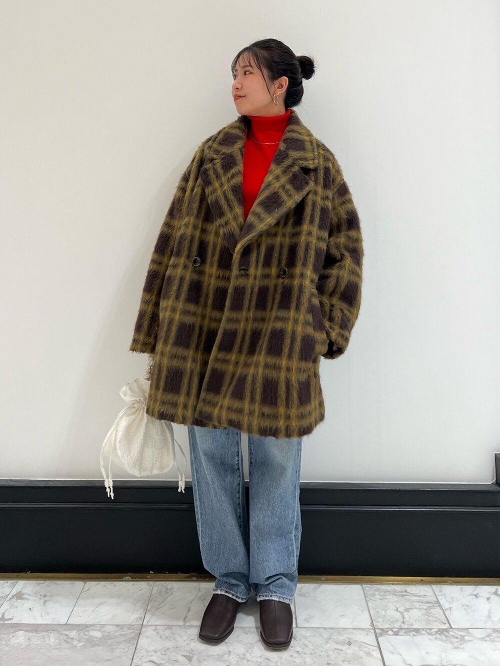 レッド系のニット/セーター、ホワイト系のハンドバッグ、ブルー系のデニムパンツを着用したレディースの冬コーディネートの9枚目の写真