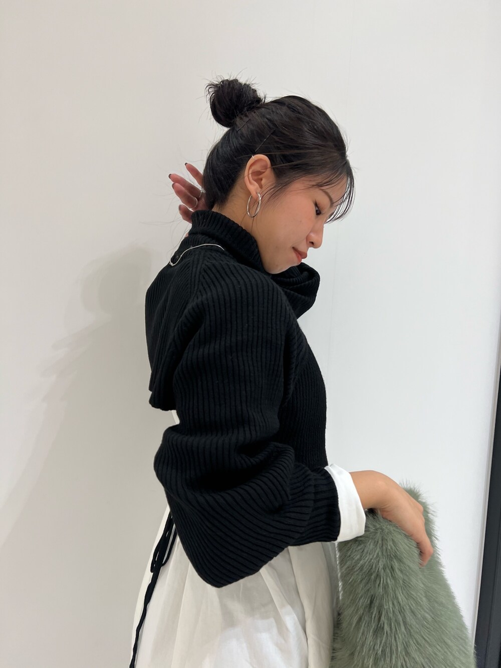 ブラック系のワンピース、グリーン系のハンドバッグ、ブラウン系のブーツを着用したレディースの冬コーディネートの8枚目の写真