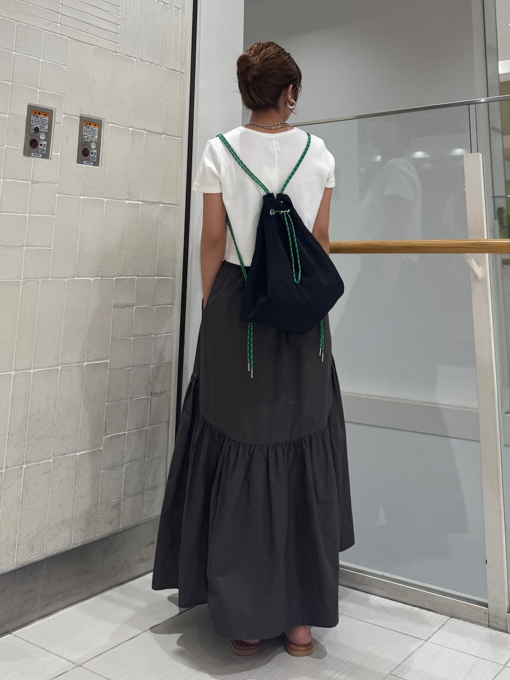 グレー系のスカート、シルバー系のサンダル、ホワイト系のTシャツ/カットソーを着用したレディースの春コーディネートの6枚目の写真