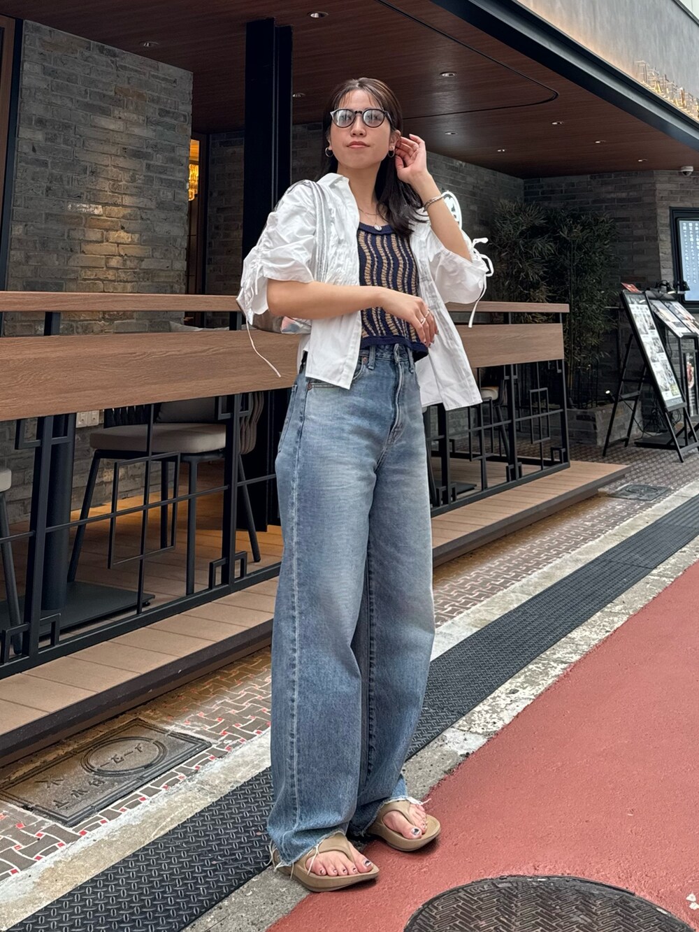 ブルー系のデニムパンツ、ホワイト系のシャツ/ブラウス、シルバー系のハンドバッグを着用したレディースの春コーディネートの2枚目の写真