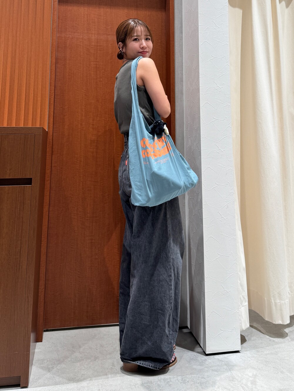 ブラック系のデニムパンツ、グレー系のタンクトップ、ブルー系のトートバッグを着用したレディースの夏コーディネートの2枚目の写真