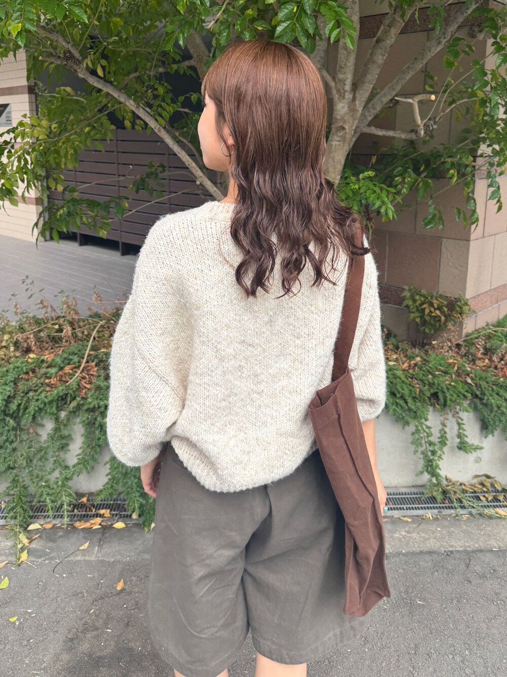 グレー系のチノパンツ、ホワイト系のニット/セーター、ブラウン系のトートバッグを着用したレディースの秋コーディネートの8枚目の写真