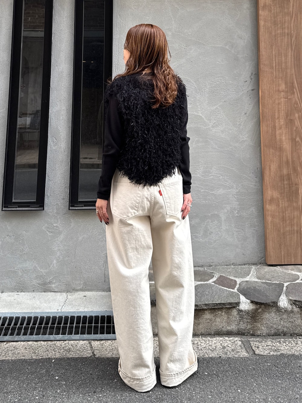 ホワイト系のデニムパンツ、ブラック系のニット/セーター、ブラック系のTシャツ/カットソーを着用したレディースの冬コーディネートの4枚目の写真