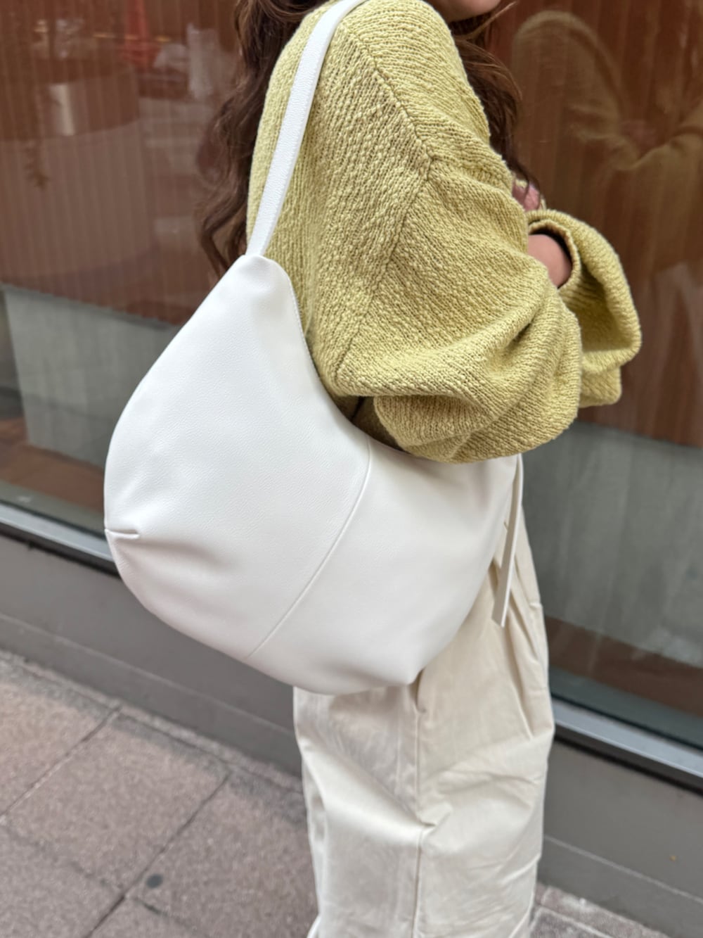 ホワイト系のチノパンツ、グリーン系のニット/セーター、ホワイト系のショルダーバッグを着用したレディースの冬コーディネートの10枚目の写真