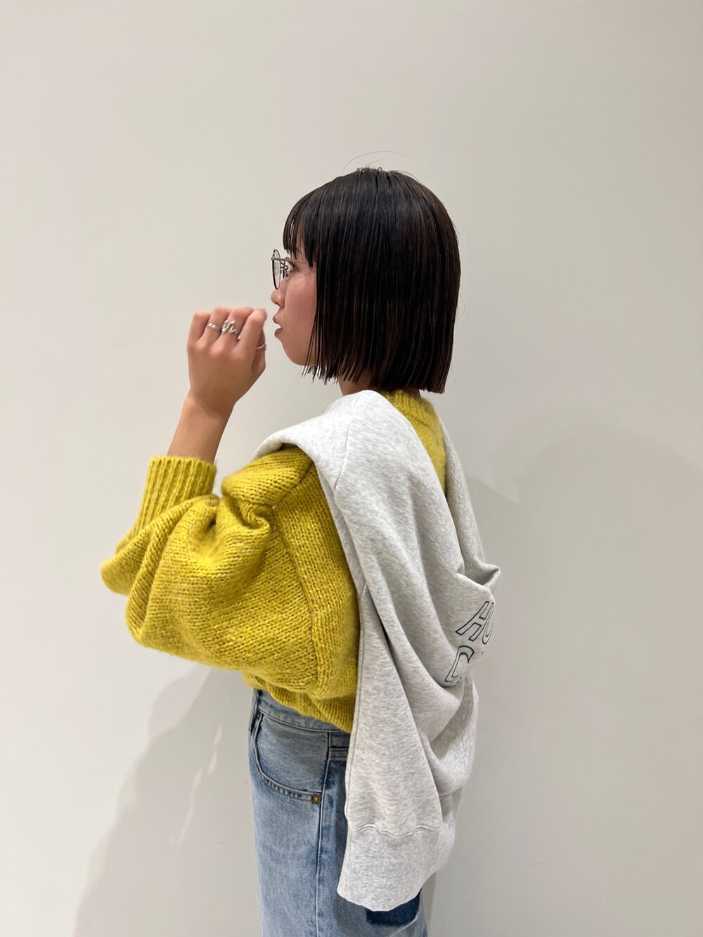 ブルー系のデニムパンツ、イエロー系のニット/セーター、グレー系のスウェットを着用したレディースの冬コーディネートの9枚目の写真