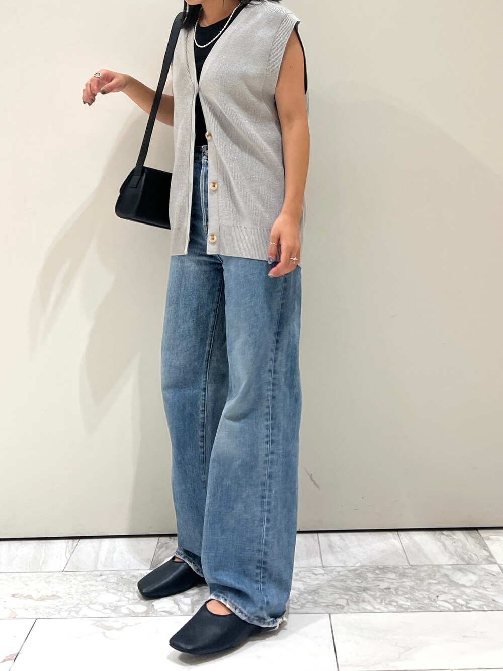 ブルー系のデニムパンツ、ブラック系のショルダーバッグ、シルバー系のベストを着用したレディースの夏コーディネートの5枚目の写真