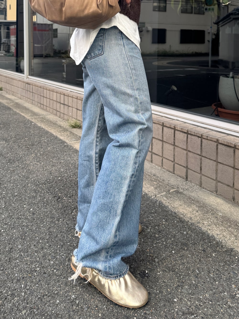 ホワイト系のTシャツ/カットソー、ブラウン系のニット/セーター、ブルー系のデニムパンツを着用したレディースの秋コーディネートの8枚目の写真