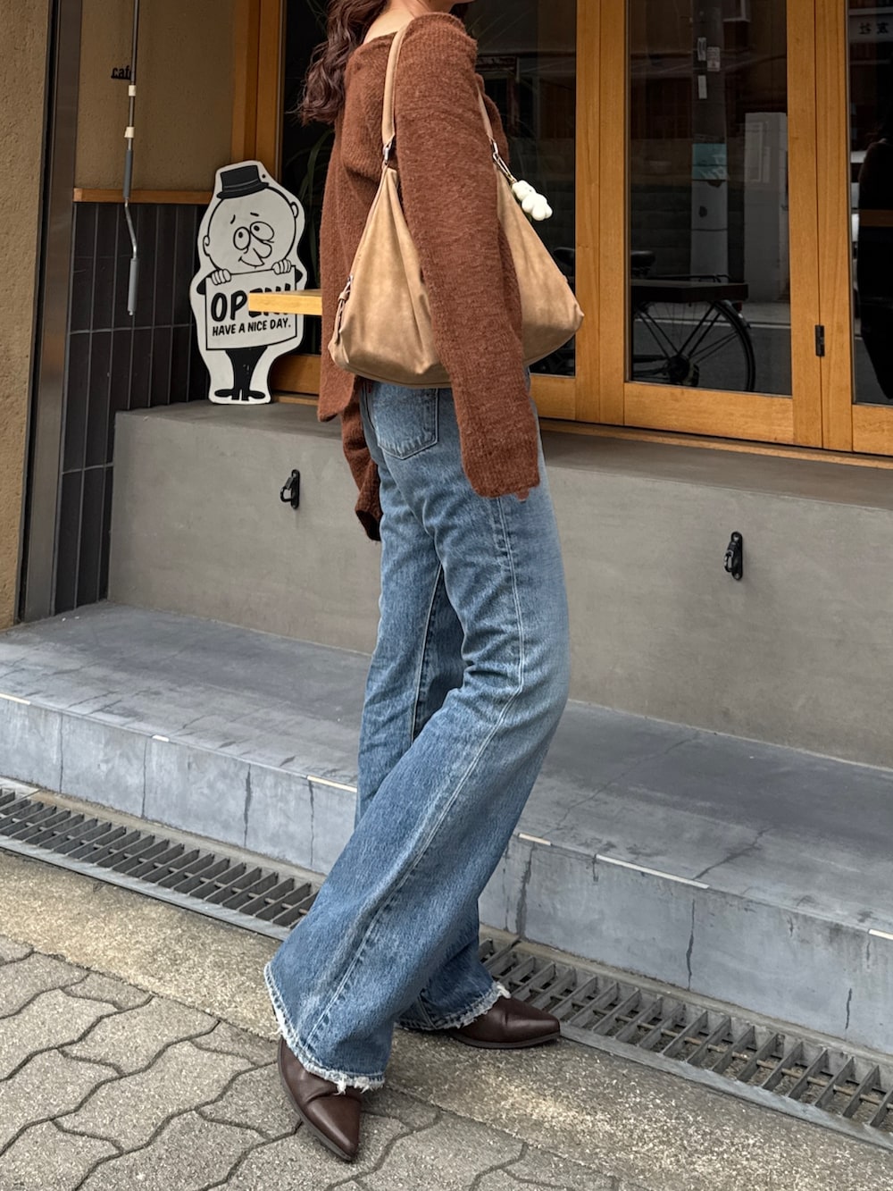 ブルー系のデニムパンツ、ブラウン系のブーツ、ブラウン系のニット/セーターを着用したレディースの秋コーディネートの6枚目の写真