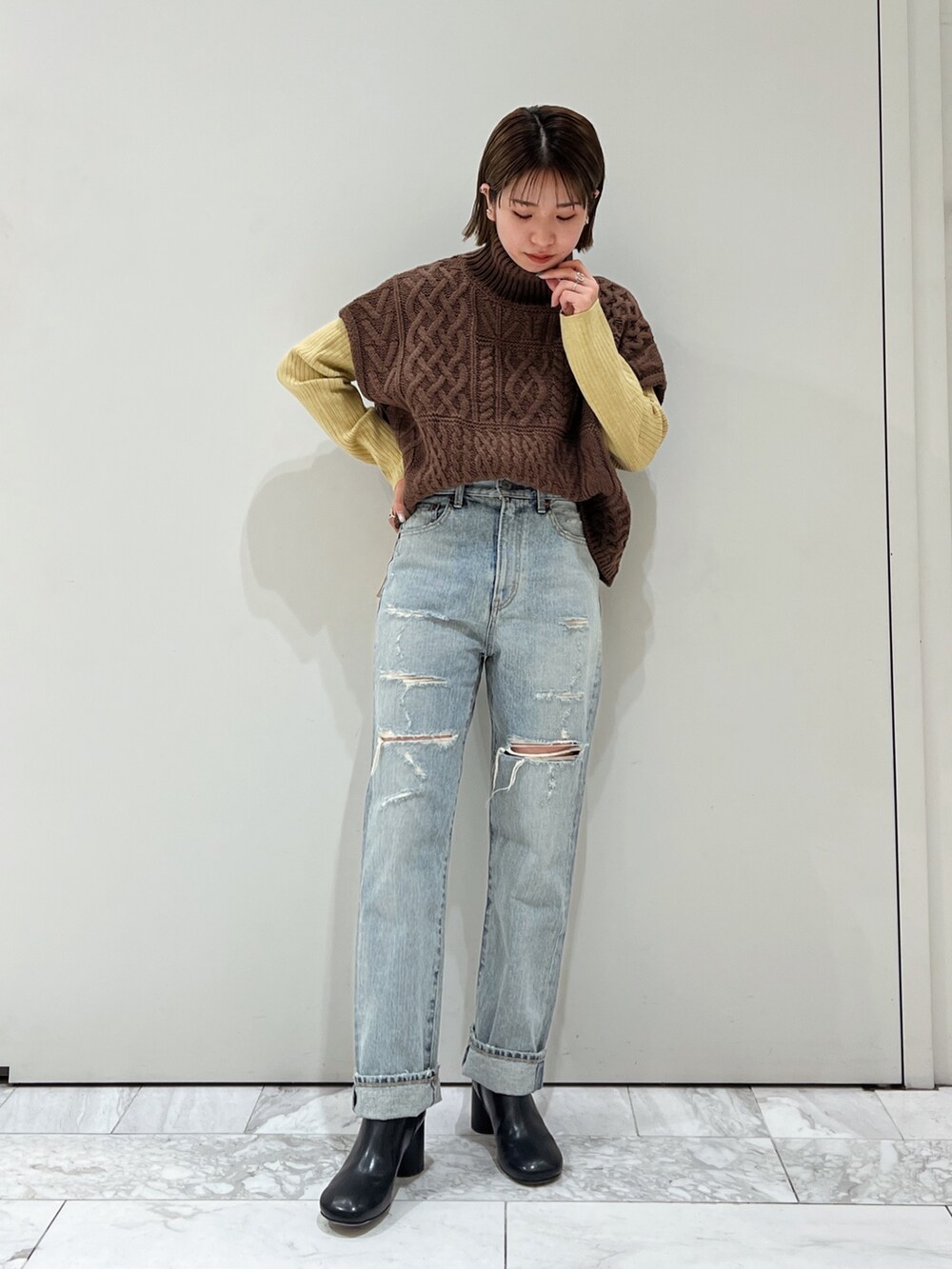 ブラウン系のニット/セーター、ブルー系のデニムパンツ、ブラック系のブーツを着用したレディースの冬コーディネートの2枚目の写真