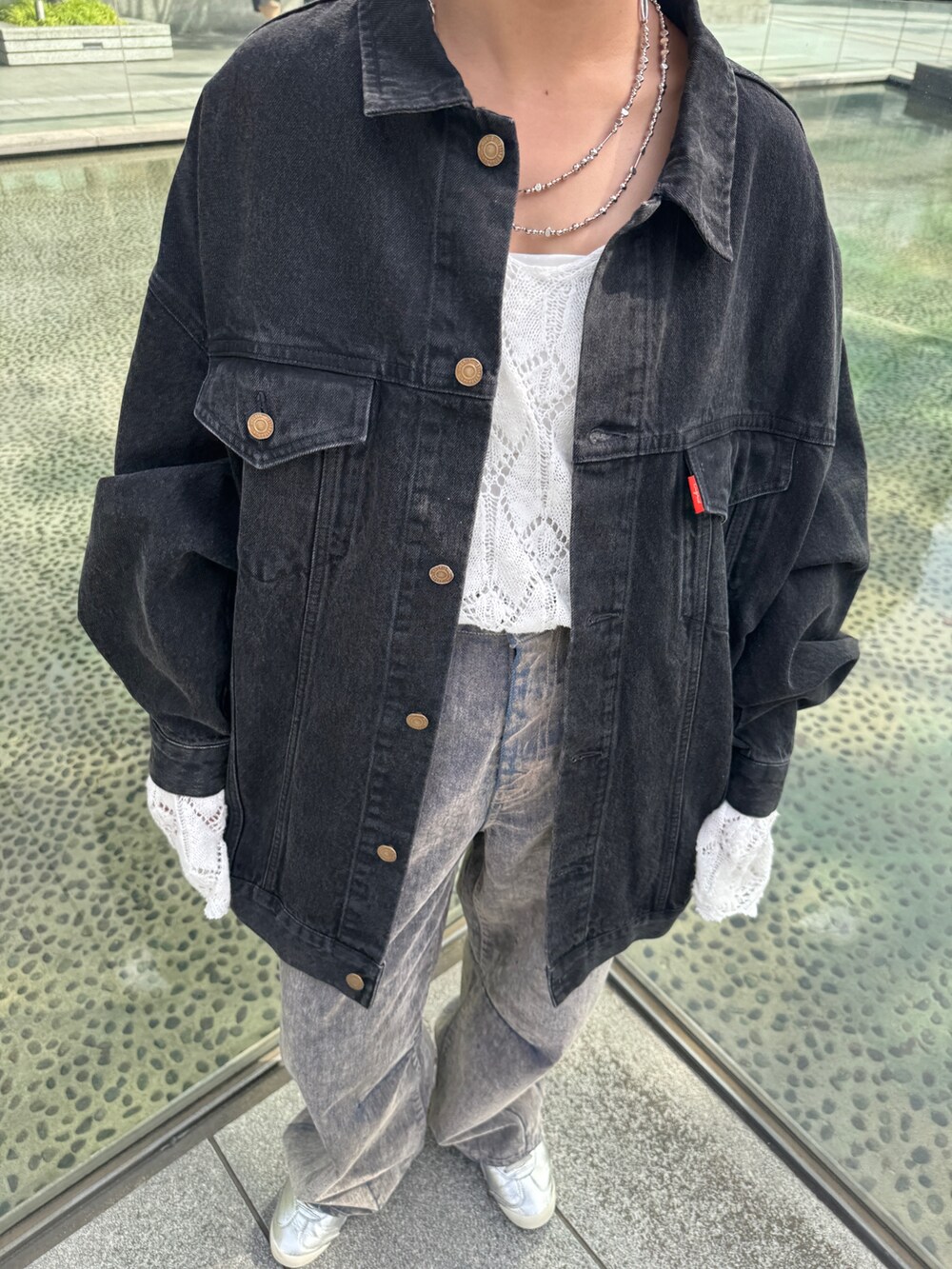 ホワイト系のニット/セーター、ベージュ系のデニムパンツ、ブラック系のデニムジャケットを着用したレディースの夏コーディネートの9枚目の写真