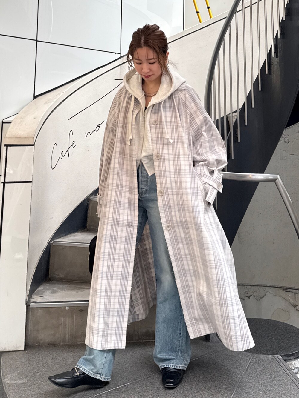 その他のステンカラーコート、ブラック系のボストンバッグ、ホワイト系のパーカーを着用したレディースの冬コーディネートの2枚目の写真