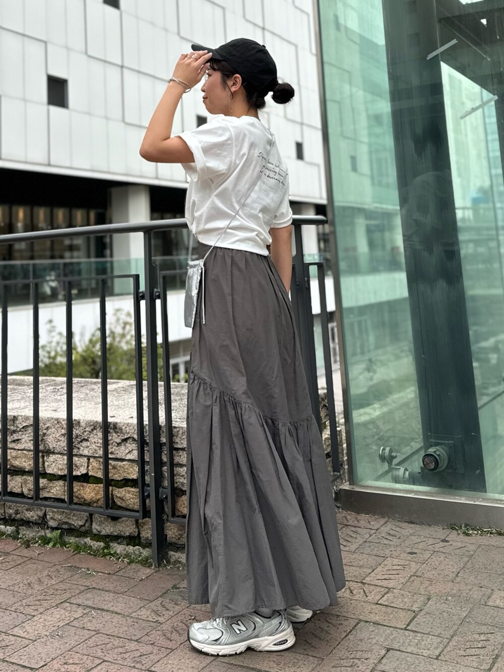 シルバー系のショルダーバッグ、ホワイト系のTシャツ/カットソー、グレー系のスカートを着用したレディースの春コーディネートの7枚目の写真