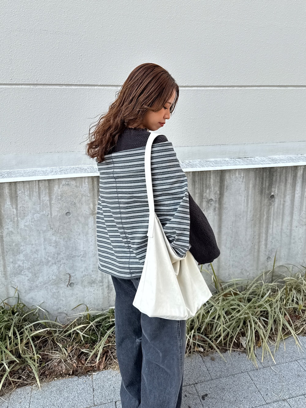 グレー系のニット/セーター、グレー系のTシャツ/カットソー、ブラック系のデニムパンツを着用したレディースの冬コーディネートの8枚目の写真