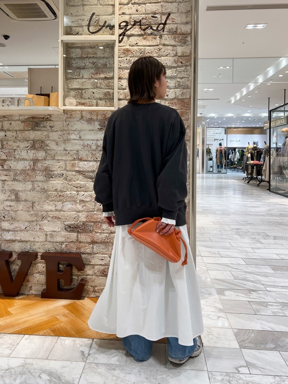 グレー系のスウェット、ブラック系のワンピース、ブルー系のデニムパンツを着用したレディースの冬コーディネートの4枚目の写真