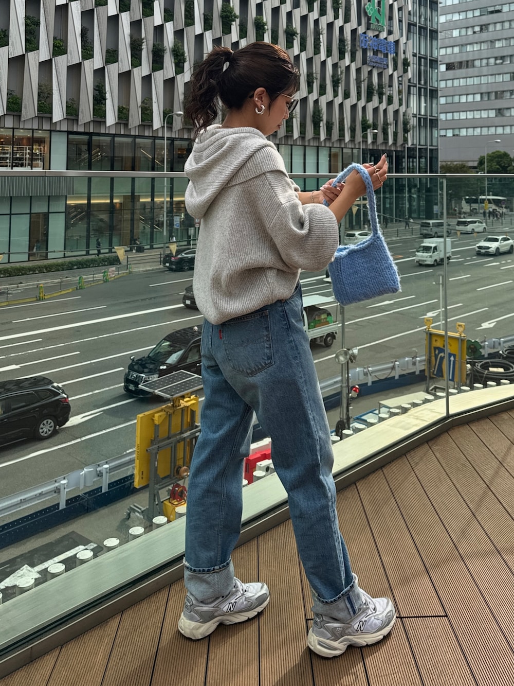 ブルー系のハンドバッグ、グレー系のニット/セーター、ブルー系のデニムパンツを着用したレディースの秋コーディネートの7枚目の写真