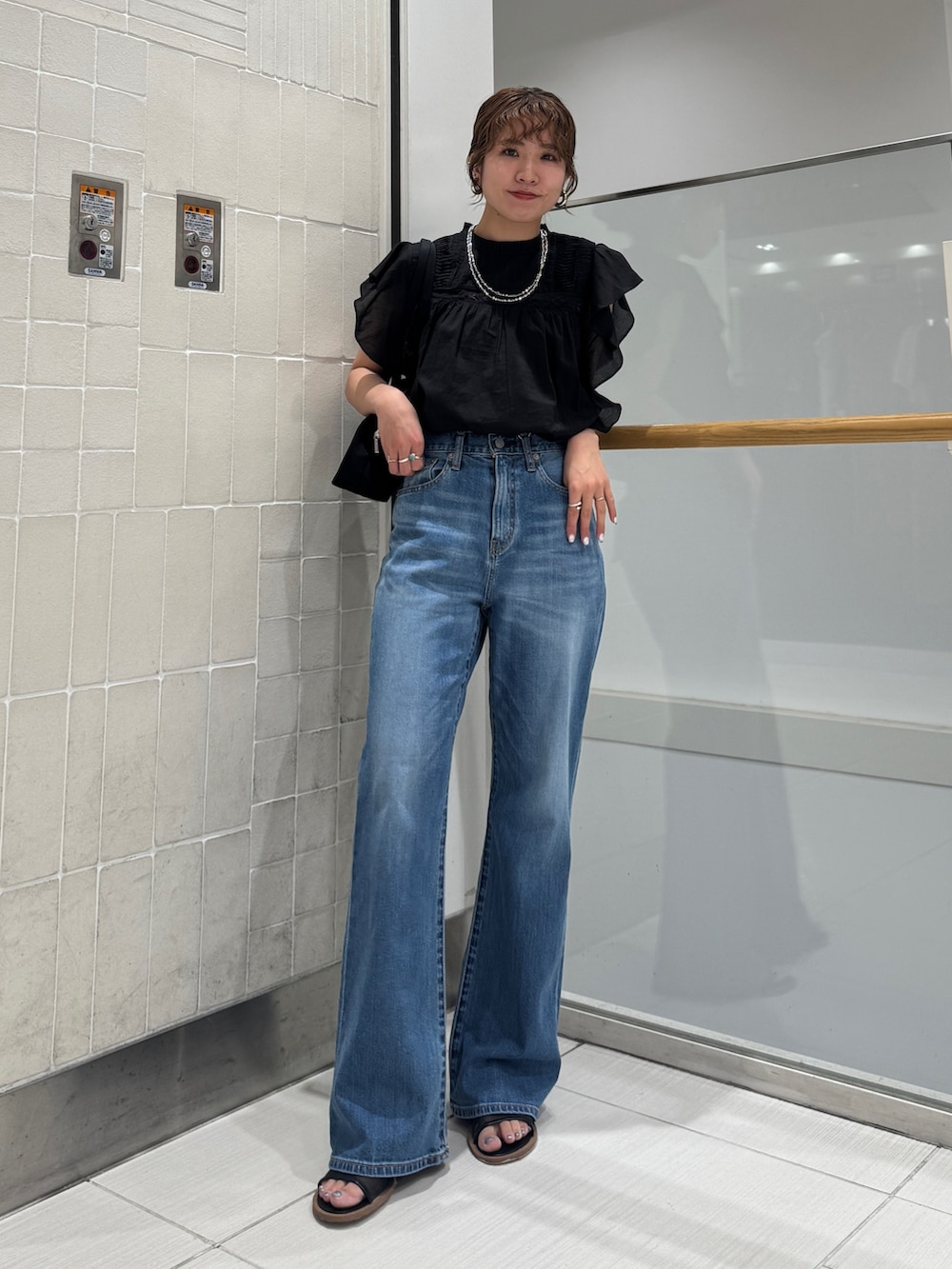ブルー系のデニムパンツ、ブラック系のシャツ/ブラウス、ブラック系のハンドバッグを着用したレディースの春コーディネートの7枚目の写真