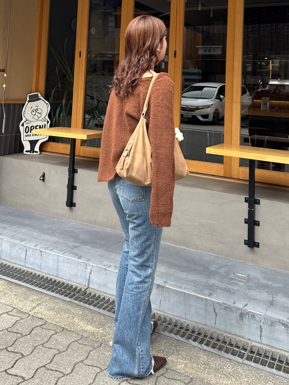 ブルー系のデニムパンツ、ブラウン系のブーツ、ブラウン系のニット/セーターを着用したレディースの秋コーディネートの4枚目の写真