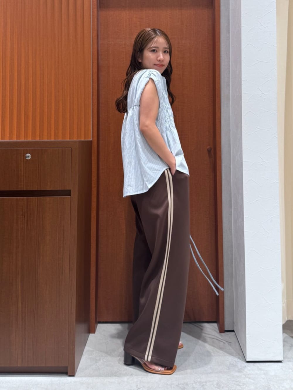 その他のサンダル、ブラウン系のその他パンツ、ブルー系のハンドバッグを着用したレディースの夏コーディネートの2枚目の写真