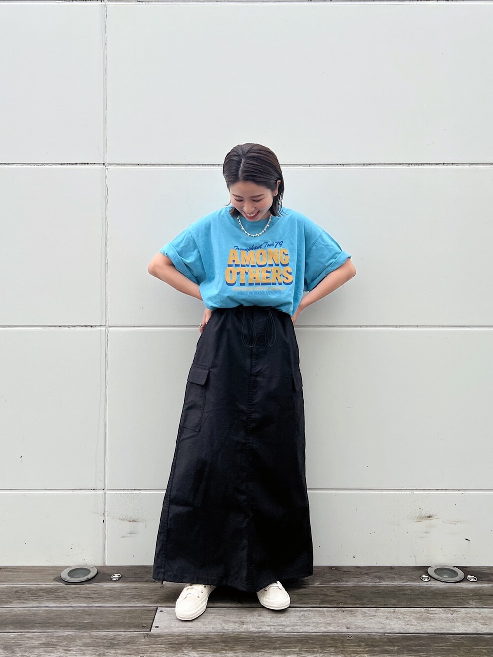 ブルー系のTシャツ/カットソー、ブラック系のスカート、ホワイト系のスニーカーを着用したレディースの春コーディネートの4枚目の写真