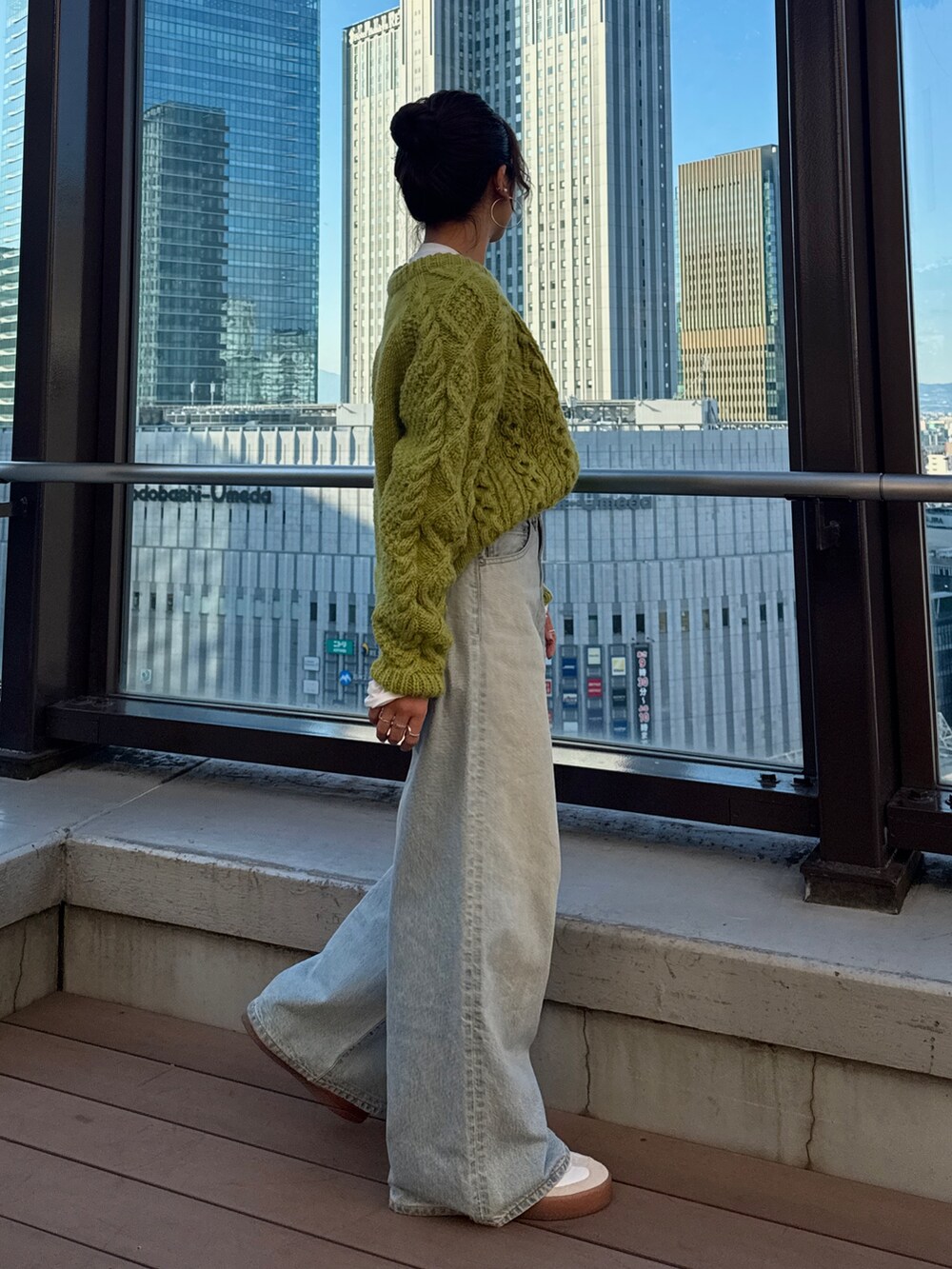グリーン系のニット/セーター、ホワイト系のTシャツ/カットソー、ブルー系のデニムパンツを着用したレディースの冬コーディネートの4枚目の写真