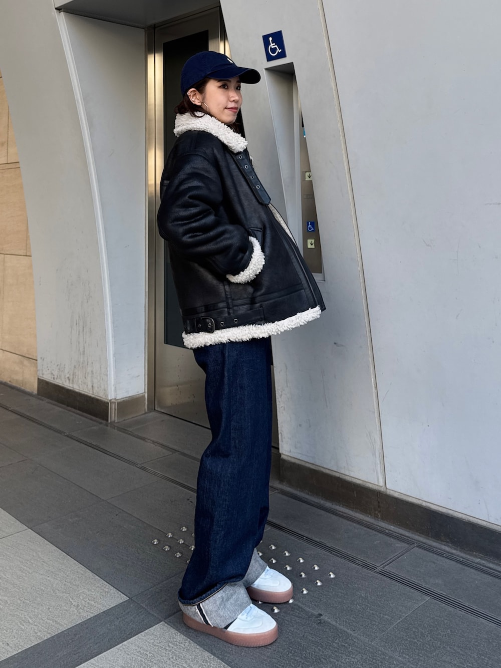 ブルー系のデニムパンツ、ホワイト系のカーディガン/ボレロ、ブラック系のブルゾンを着用したレディースの冬コーディネートの7枚目の写真