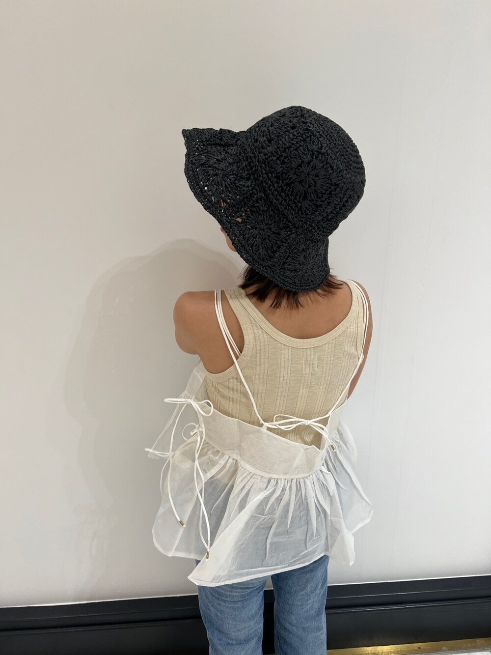 ホワイト系のシャツ/ブラウス、ベージュ系のタンクトップ、ブルー系のデニムパンツを着用したレディースの春コーディネートの6枚目の写真