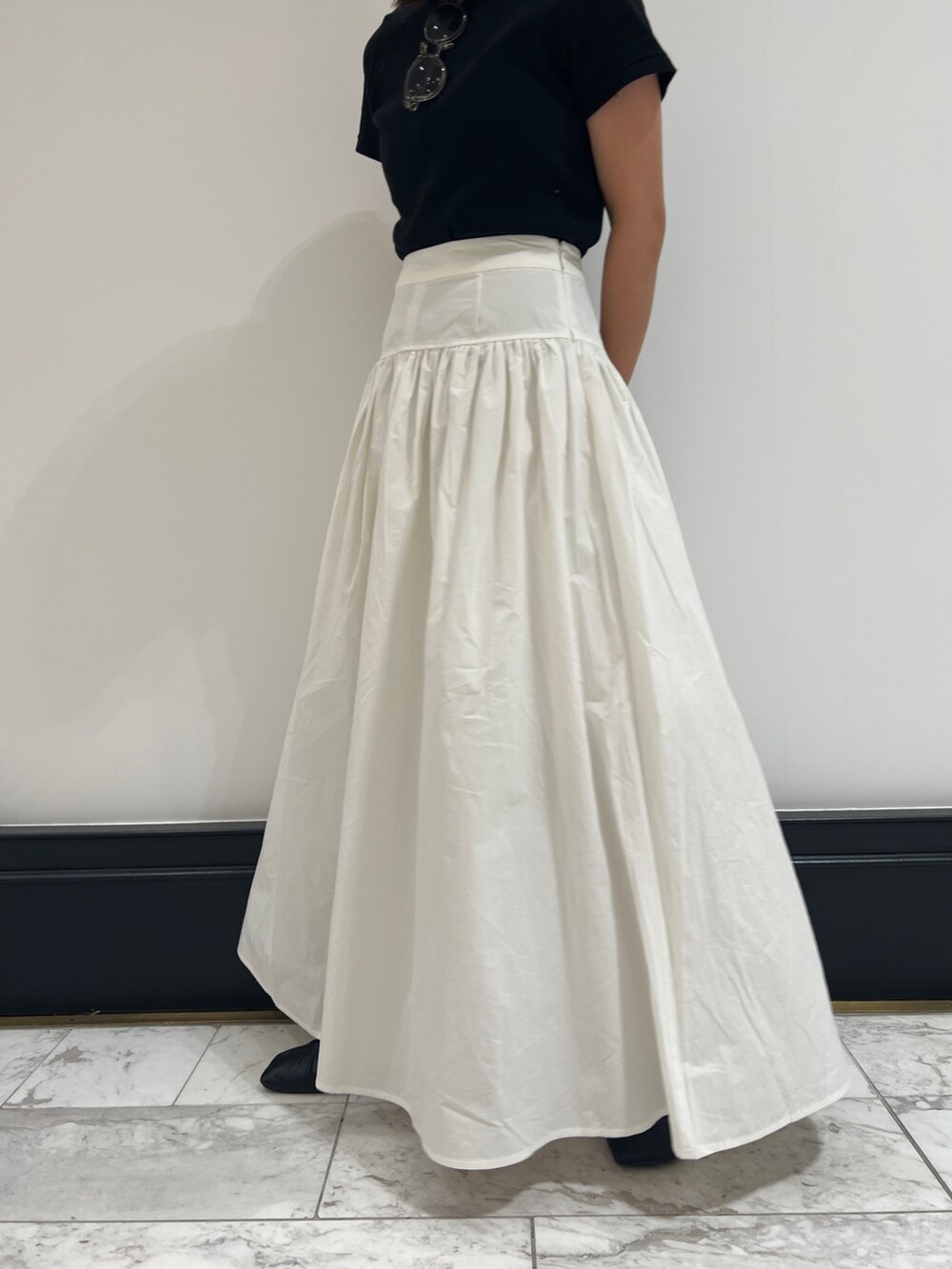 ホワイト系のスカート、ブラック系のTシャツ/カットソー、ブラック系のパンプスを着用したレディースの春コーディネートの8枚目の写真