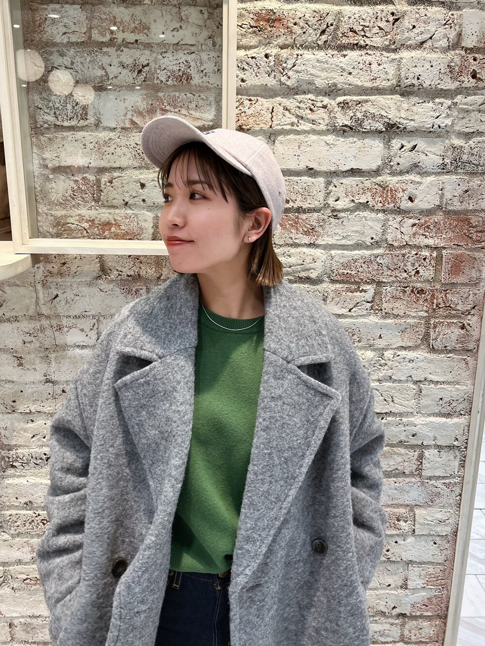 グレー系のチェスターコート、グリーン系のニット/セーター、グレー系のキャップを着用したレディースの冬コーディネートの8枚目の写真