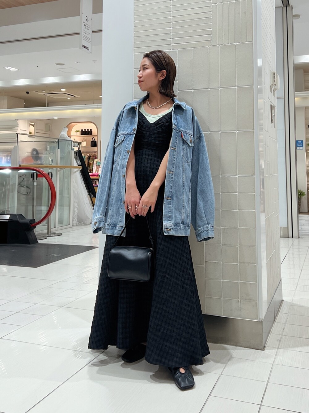 ブラック系のワンピース、グリーン系のタンクトップ、ブルー系のデニムジャケットを着用したレディースの冬コーディネートの7枚目の写真