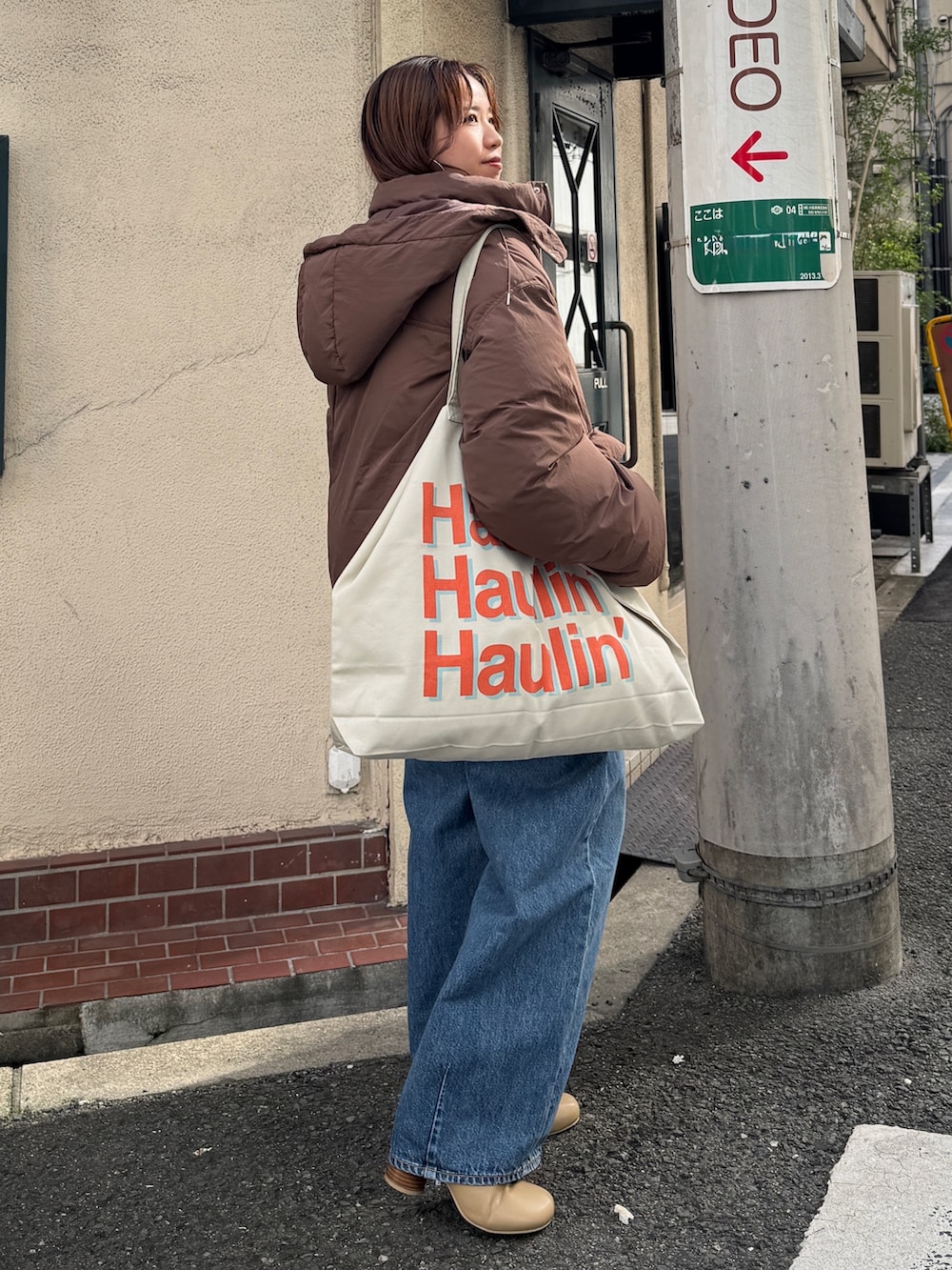 ブラウン系のダウンジャケット/コート、ホワイト系のニット/セーター、ブルー系のデニムパンツを着用したレディースの秋コーディネートの3枚目の写真