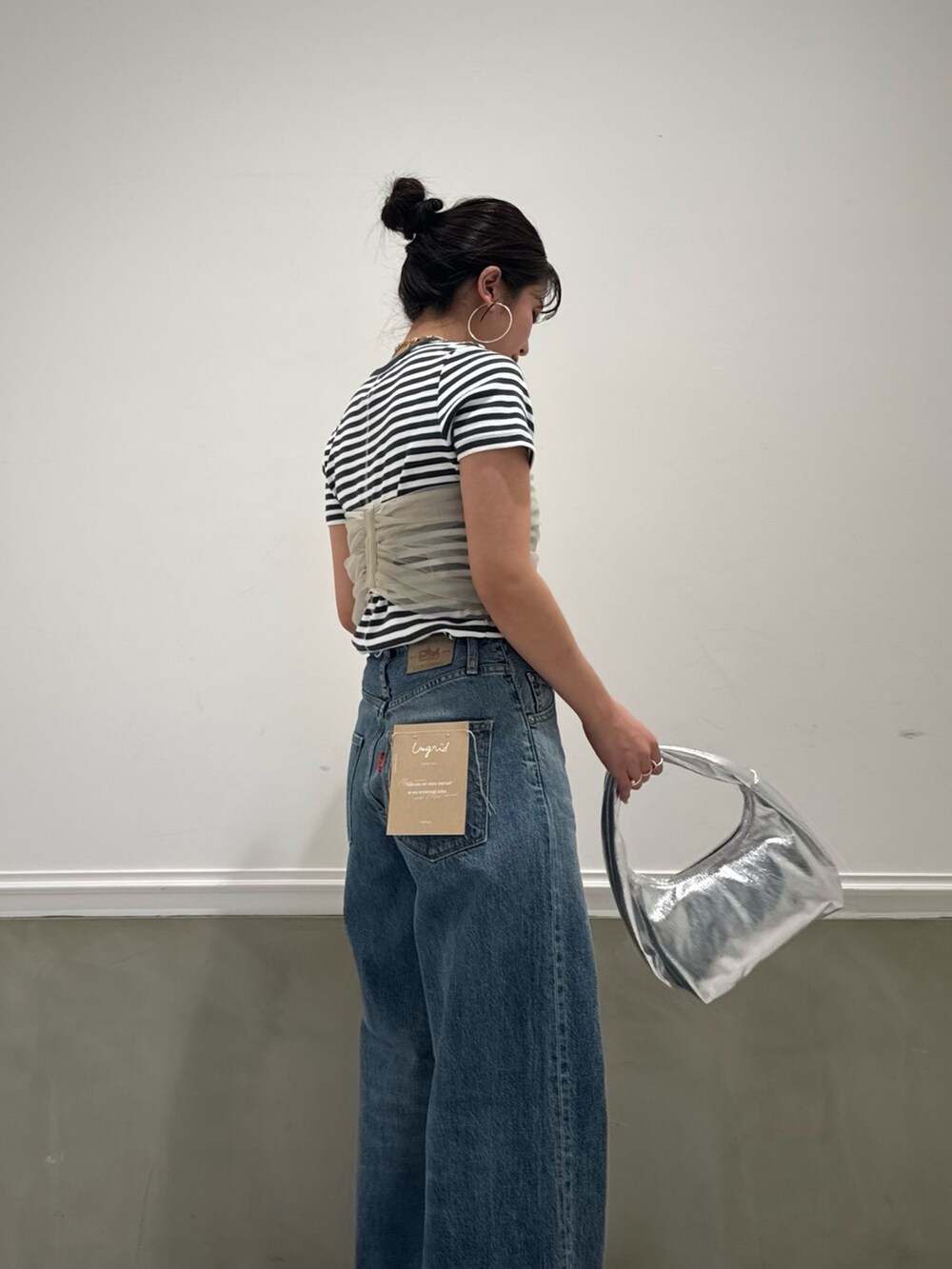 グレー系のTシャツ/カットソー、ベージュ系のキャミソール、ブルー系のデニムパンツを着用したレディースの春コーディネートの3枚目の写真