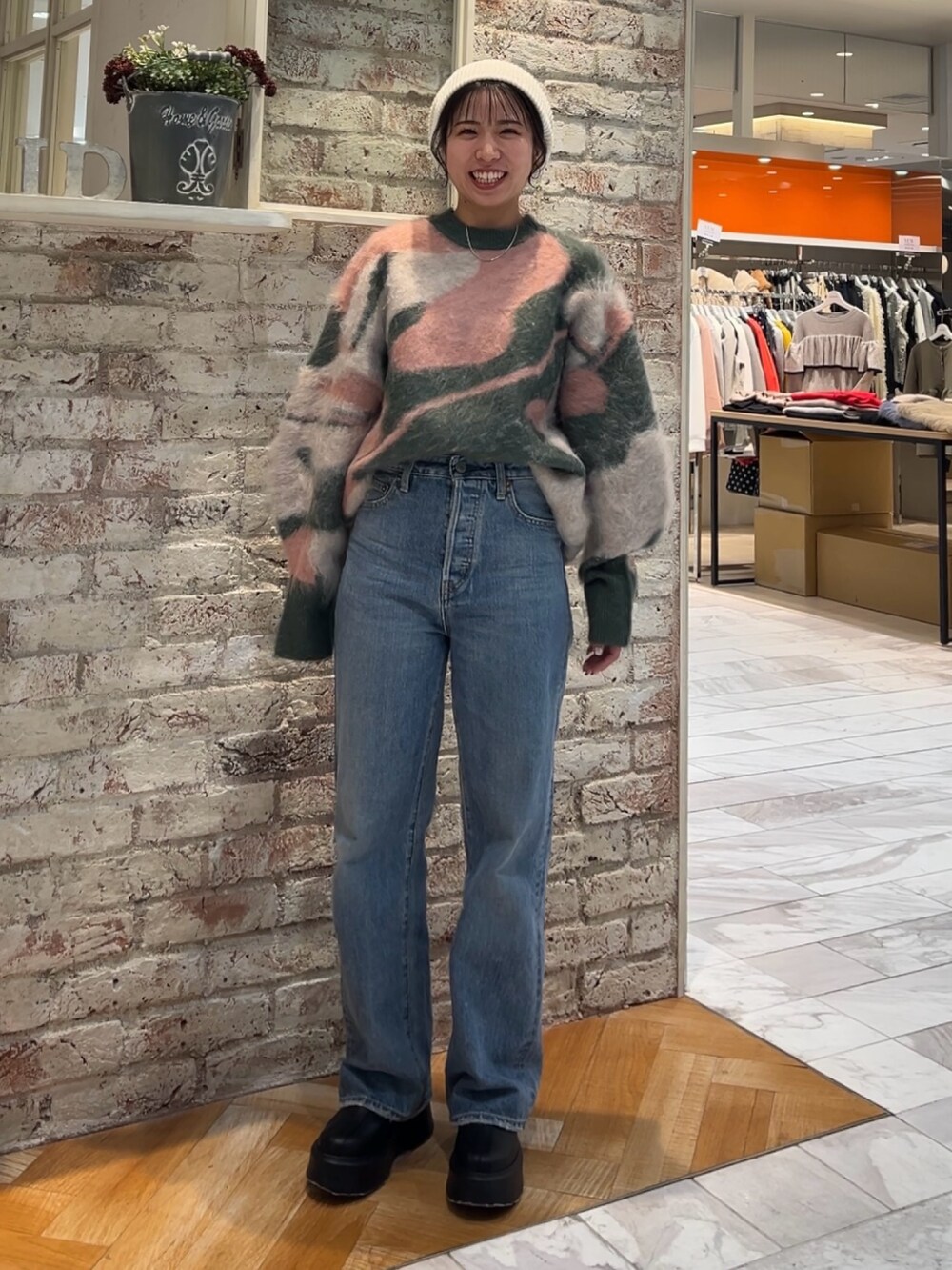 ブラック系のブーツ、グリーン系のニット/セーター、ブルー系のデニムパンツを着用したレディースの秋コーディネートの6枚目の写真