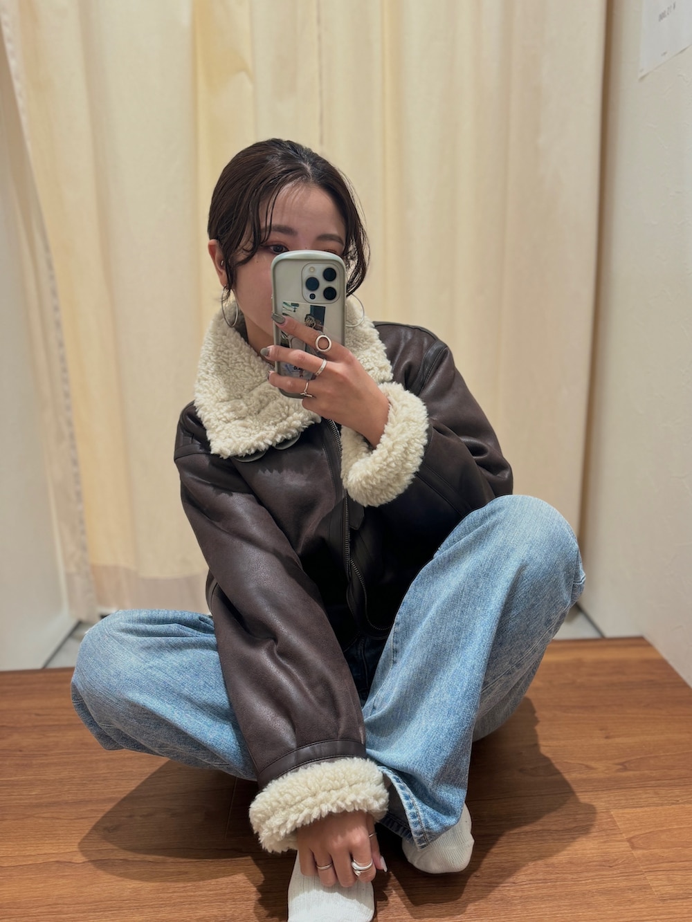 ブルー系のデニムパンツ、ブラウン系のブルゾン、ホワイト系のニット/セーターを着用したレディースの秋コーディネートの5枚目の写真