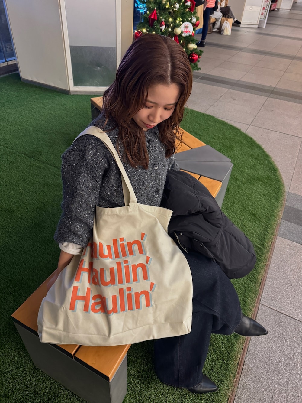 グレー系のカーディガン/ボレロ、ブラック系のダウンジャケット/コート、ホワイト系のトートバッグを着用したレディースの冬コーディネートの8枚目の写真