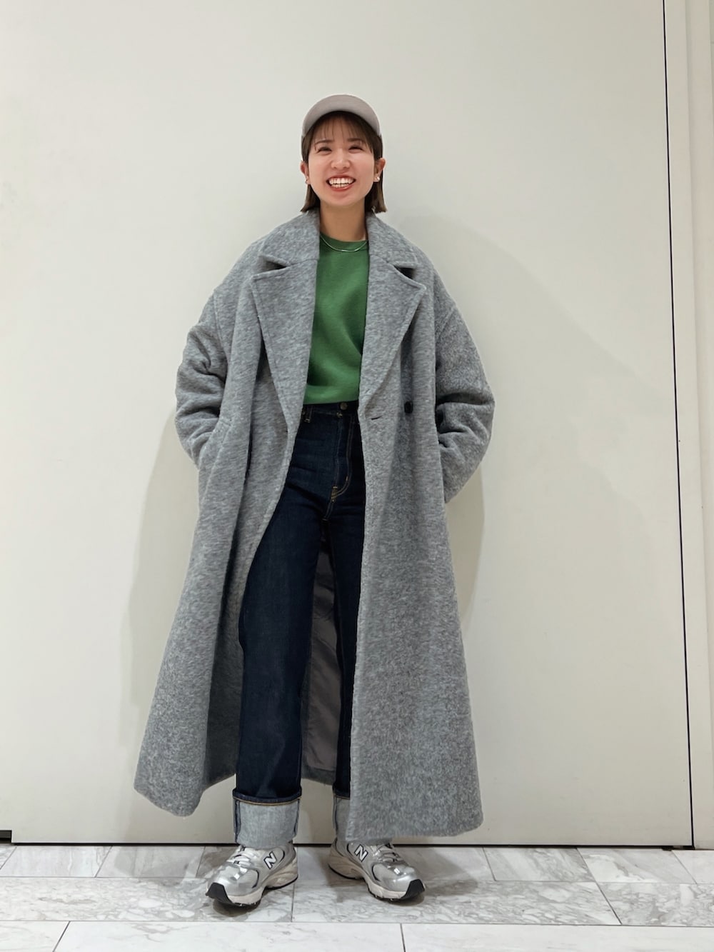 グレー系のチェスターコート、グリーン系のニット/セーター、グレー系のキャップを着用したレディースの冬コーディネートの7枚目の写真