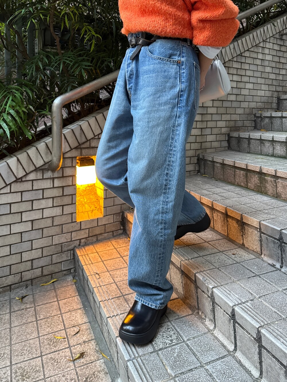 オレンジ系のニット/セーター、ホワイト系のダウンジャケット/コート、ブルー系のデニムパンツを着用したレディースの冬コーディネートの10枚目の写真
