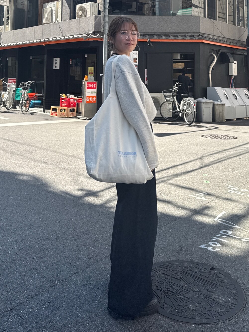 ブルー系のデニムパンツ、ホワイト系のニット/セーター、ホワイト系のトートバッグを着用したレディースの夏コーディネートの4枚目の写真