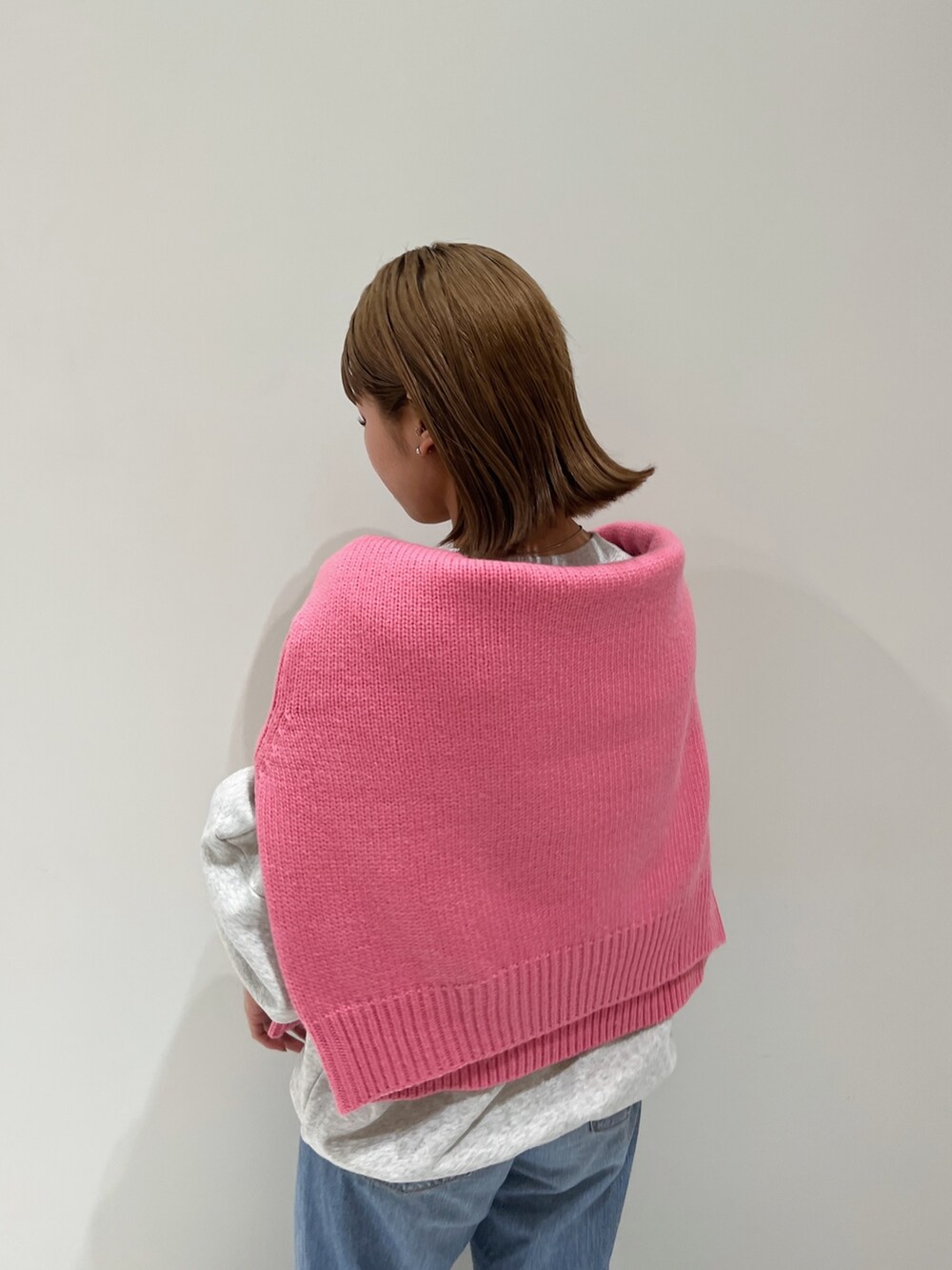 ピンク系のニット/セーター、グレー系のスウェット、ブルー系のデニムパンツを着用したレディースの秋コーディネートの7枚目の写真