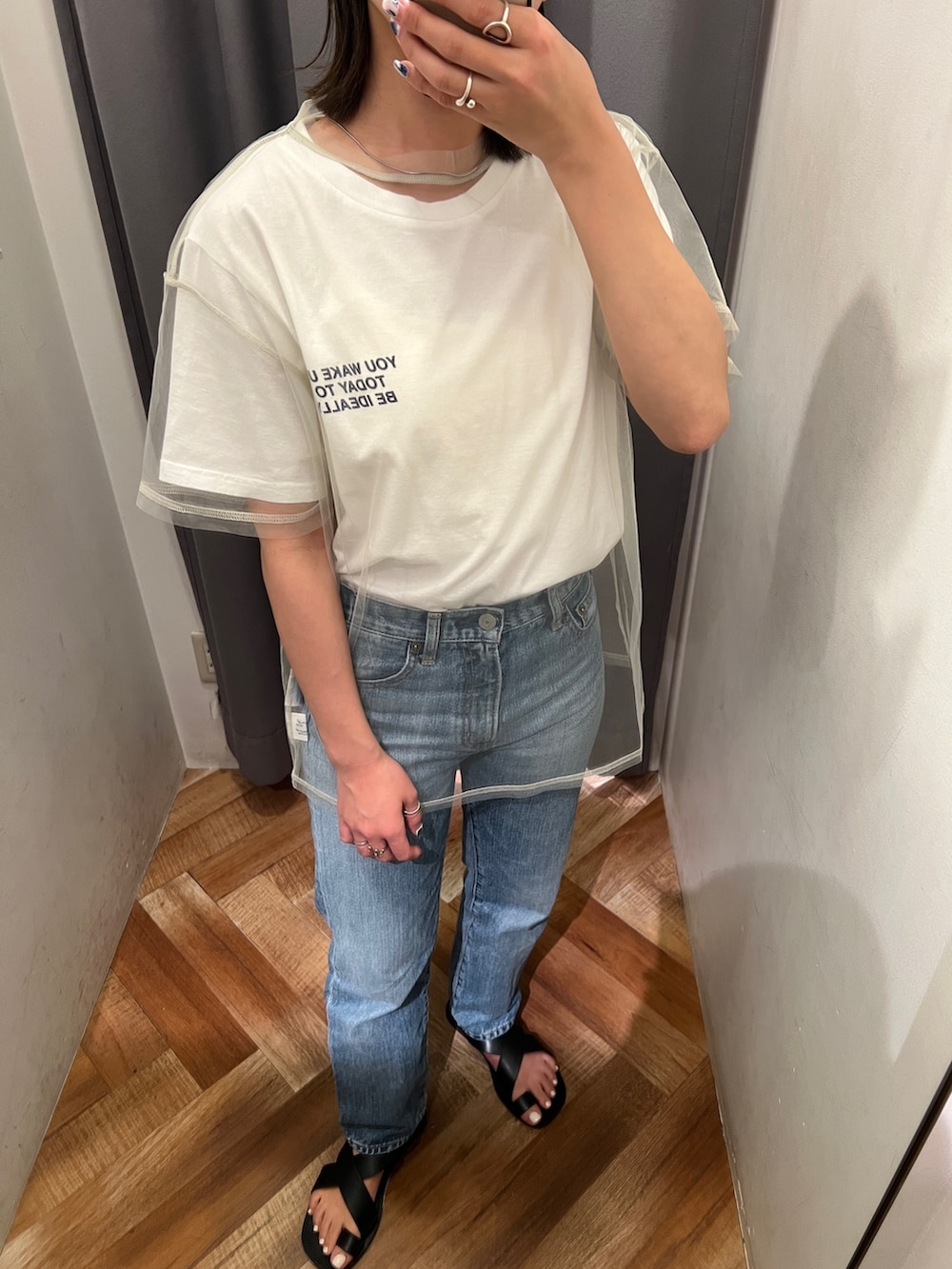 ブルー系のデニムパンツ、ブラック系のサンダル、ホワイト系のTシャツ/カットソーを着用したレディースの春コーディネートの6枚目の写真