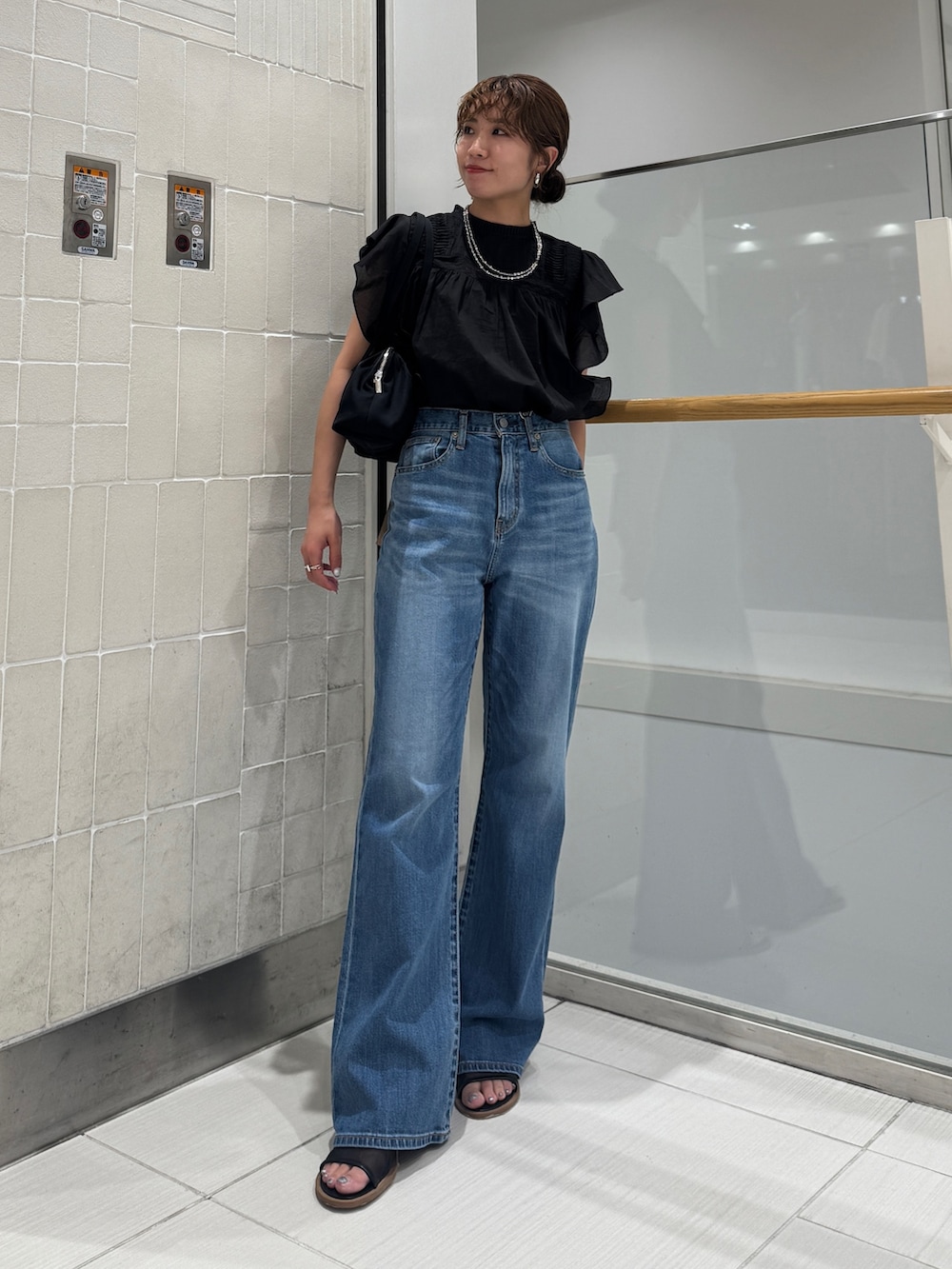 ブルー系のデニムパンツ、ブラック系のシャツ/ブラウス、ブラック系のハンドバッグを着用したレディースの春コーディネートの8枚目の写真