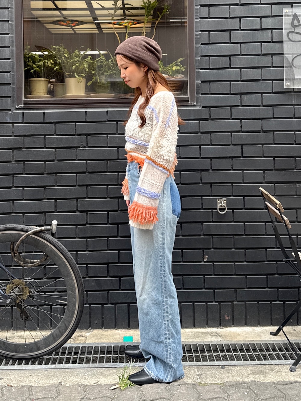 ブルー系のデニムパンツ、ホワイト系のニット/セーター、ブラック系のサンダルを着用したレディースの秋コーディネートの3枚目の写真