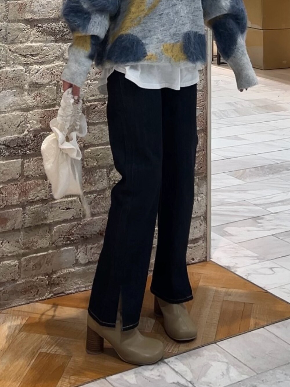 ブルー系のニット/セーター、ホワイト系のハンドバッグ、ブルー系のデニムパンツを着用したレディースの秋コーディネートの8枚目の写真