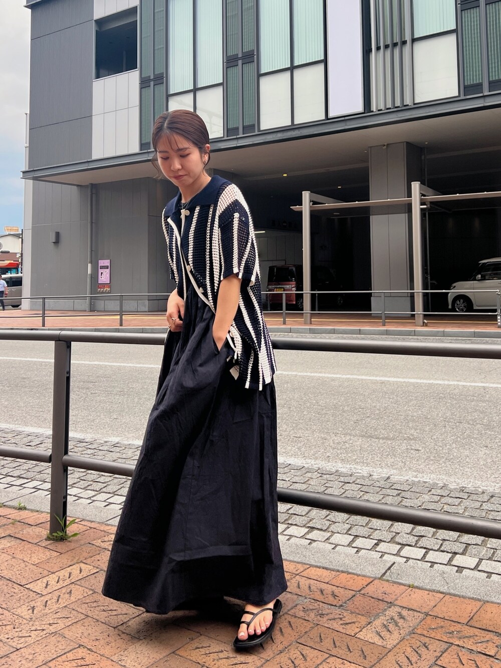 ブラック系のワンピース、ブルー系のカーディガン/ボレロ、ブラック系のサンダルを着用したレディースの春コーディネートの2枚目の写真