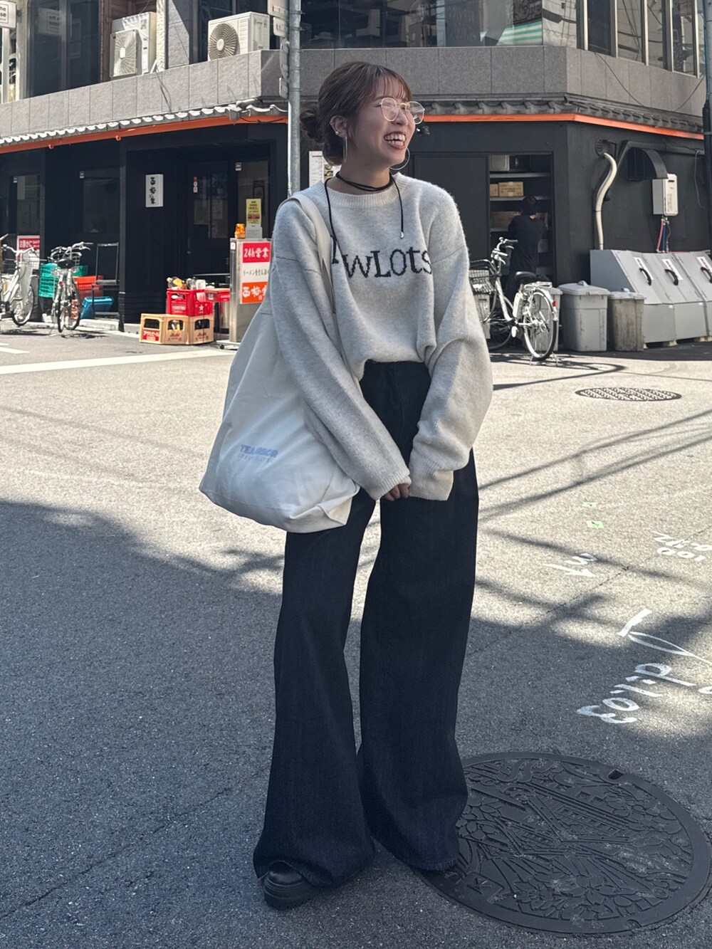 ブルー系のデニムパンツ、ホワイト系のニット/セーター、ホワイト系のトートバッグを着用したレディースの夏コーディネートの3枚目の写真