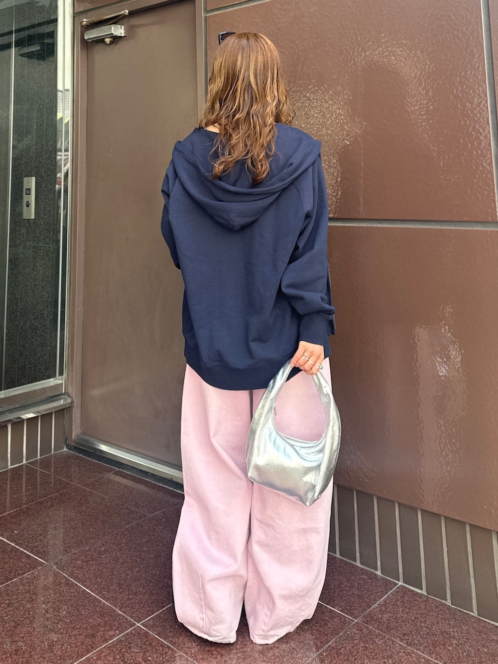 ブルー系のパーカー、ピンク系のデニムパンツ、ブラック系のキャミソールを着用したレディースの春コーディネートの4枚目の写真