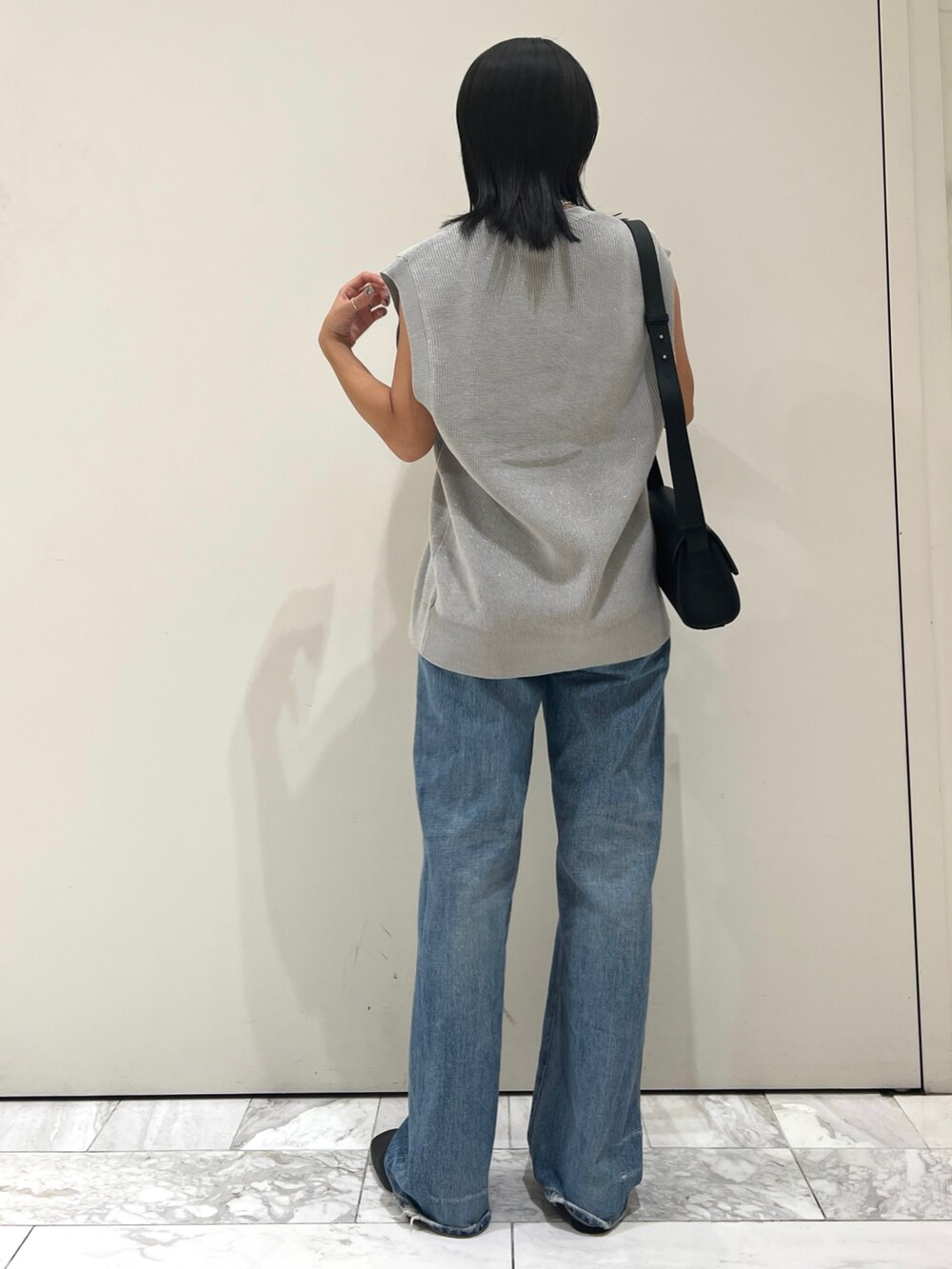 ブルー系のデニムパンツ、ブラック系のショルダーバッグ、シルバー系のベストを着用したレディースの夏コーディネートの4枚目の写真