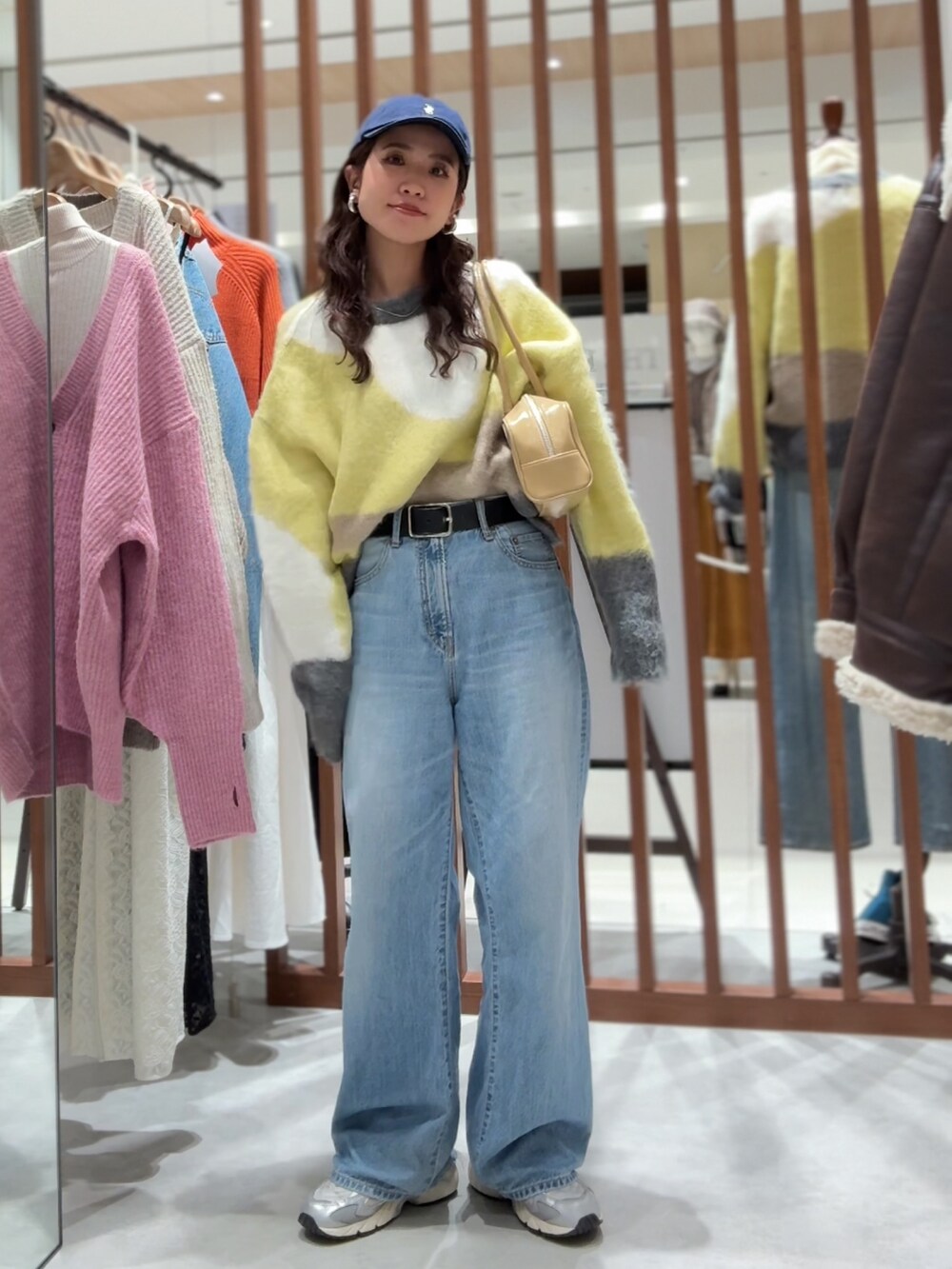 グリーン系のニット/セーター、ブルー系のデニムパンツ、ベージュ系のハンドバッグを着用したレディースの秋コーディネートの2枚目の写真