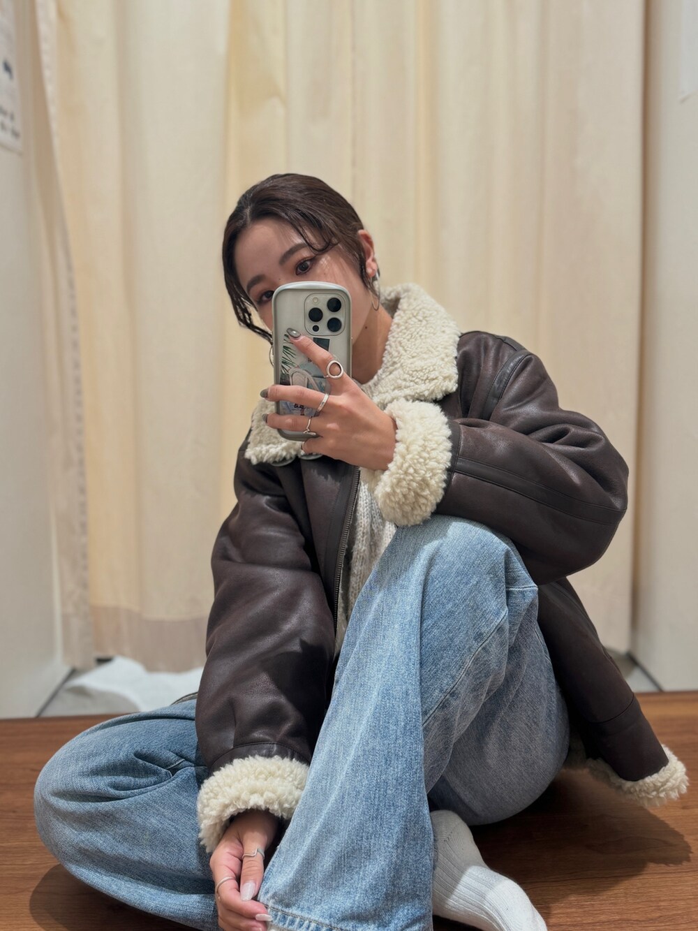 ブルー系のデニムパンツ、ブラウン系のブルゾン、ホワイト系のニット/セーターを着用したレディースの秋コーディネートの4枚目の写真