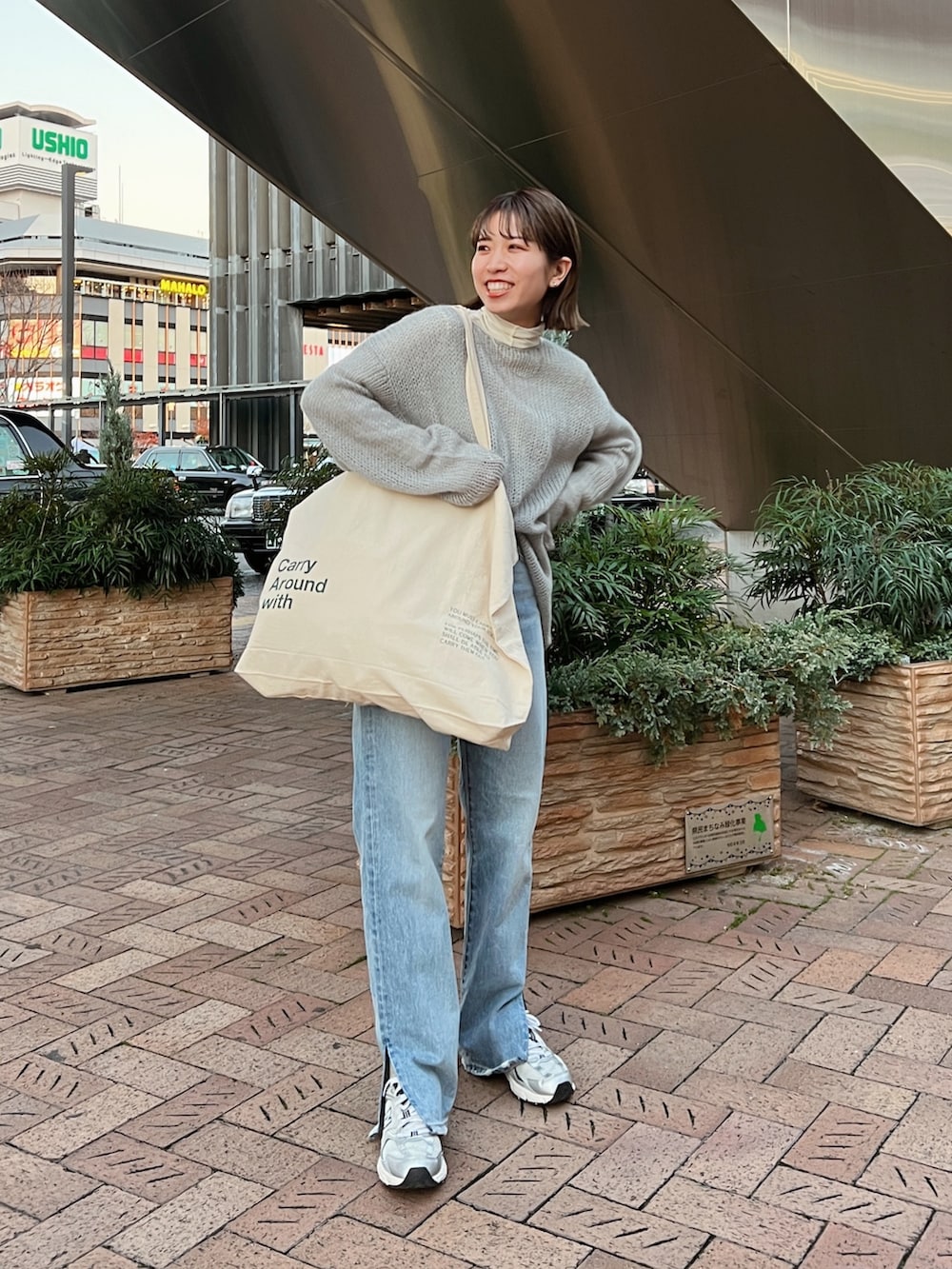 ベージュ系のムートンコート、ホワイト系のハンドバッグ、グレー系のニット/セーターを着用したレディースの冬コーディネートの10枚目の写真