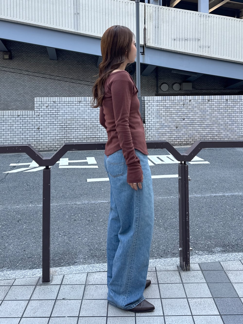 ブルー系のデニムパンツ、ブラウン系のTシャツ/カットソー、ブラウン系のブーツを着用したレディースの秋コーディネートの2枚目の写真